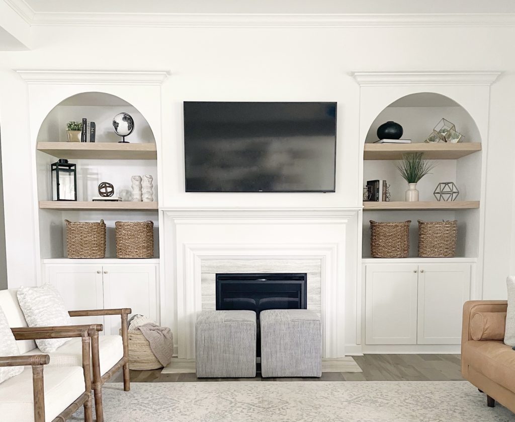 white Arched built ins with oak shelves and tv