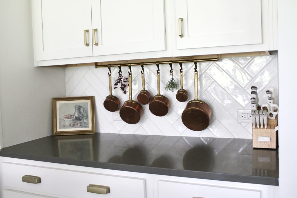 french copper pots hanging from a brass bar